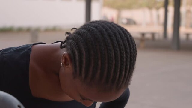 Silent dance preparation. Graceful woman adjusts costume patiently. Focused dancer with neat cornrows gets ready quietly. Poised woman adjusts her dance outfit with calm focus and graceful movements