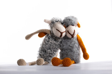 Two knitted wool sheep hugging on a white background.