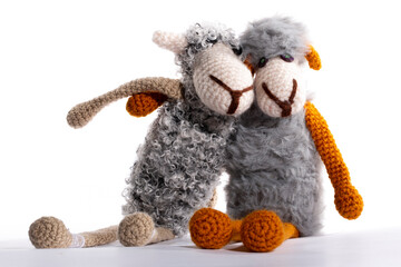 Two knitted wool sheep hugging on a white background.