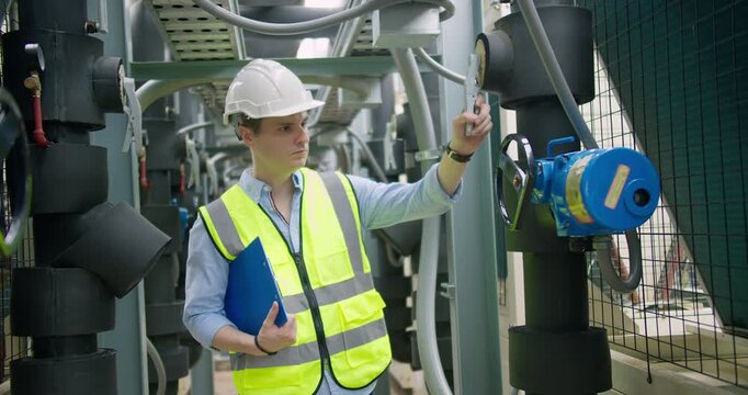 Professional engineer is inspecting industrial machinery valves in a modern plant, focusing on operational efficiency, quality control, and industrial safety compliance.