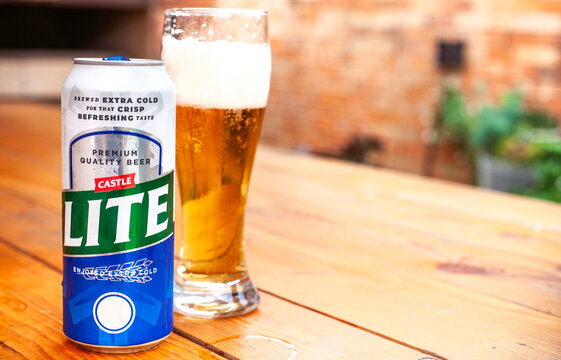 Castle Lite beer can with poured lager glass on wooden table South Africa
