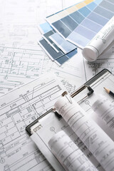 Architecture blueprints with rolled plans, compass and clipboard on desk, construction...