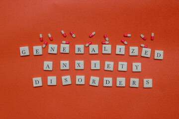 Generalized anxiety disorders text spelled with letter tiles and capsules on orange background. Mental health concept, stress, panic, and medical treatment theme. © Rio