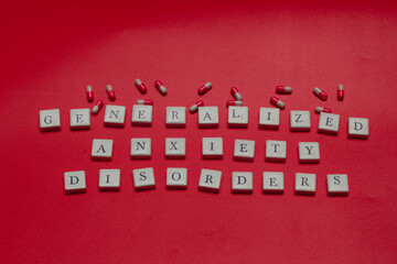 Generalized anxiety disorders text spelled with letter tiles and capsules on orange background. Mental health concept, stress, panic, and medical treatment theme. © Rio