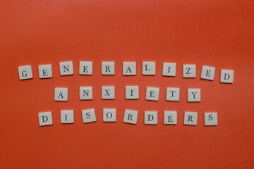 Generalized anxiety disorders text spelled with letter tiles and capsules on orange background. Mental health concept, stress, panic, and medical treatment theme. © Rio