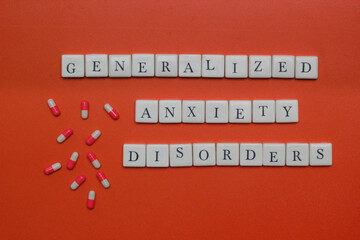 Generalized anxiety disorders text spelled with letter tiles and capsules on orange background. Mental health concept, stress, panic, and medical treatment theme. © Rio