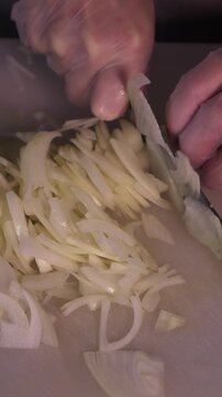 The cook's hands are cutting white onions in close-up. Cooking healthy food and homemade dishes