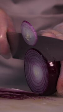 The cook's hands are cutting red onions for salad. We prepare healthy food and homemade dishes