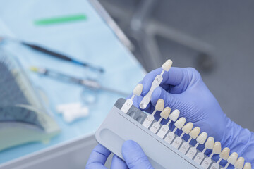 Dentist selecting tooth shade guide for whitening treatment