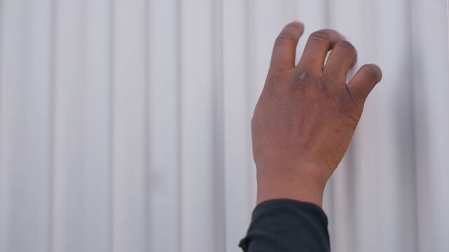 black hand covered in fine sand, fingertips brushing corrugated metal, grainy residue on skin, intimate closeup study of texture and touch frames evoke beachcomber cleaning finds, artist applying