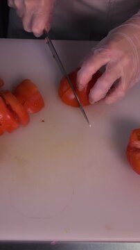 The cook is slicing red cherry tomatoes for the salad. We prepare healthy food and homemade meals