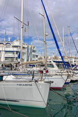 Fototapeta premium Taking a relaxing walk between moored yachts in the vibrant port of Benalmadena, Spain, surrounded by coastal charm and maritime elegance.