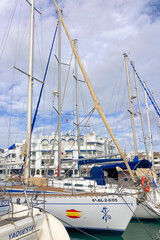 Fototapeta premium Taking a relaxing walk between moored yachts in the vibrant port of Benalmadena, Spain, surrounded by coastal charm and maritime elegance.