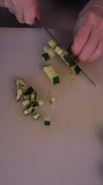 The cook is slicing a fresh cucumber for the salad. We prepare healthy food and homemade meals