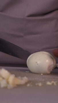 The cook cuts boiled eggs for salad. We prepare healthy meals
