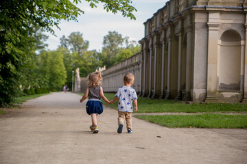 Obraz premium Back view of two little kids holding hands while walking in the park
