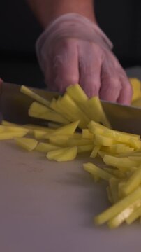 The cook is slicing potatoes for the soup. Preparation of the first courses