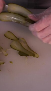 The cook is slicing a pickle for a salad. We prepare healthy food and homemade meals