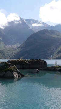 Serene lake surrounded by rocky islands and misty mountains under a cloudy sky