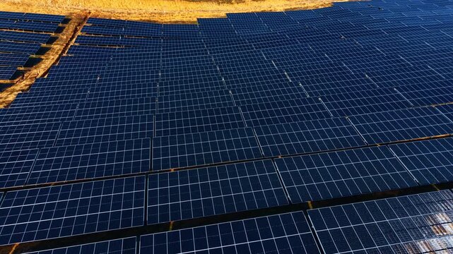 High angle close up of photovoltaic solar panel array rows. Detailed view of solar panel modules arranged in parallel lines on ground for renewable energy production.