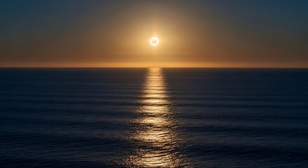 Obraz premium Sunset over the ocean with a bright orange and yellow glow reflecting on the water.