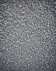 A high-angle view of small gray pebbles filling the entire frame, creating a textured surface, resembling a serene beach or rocky terrain scene in a photograph