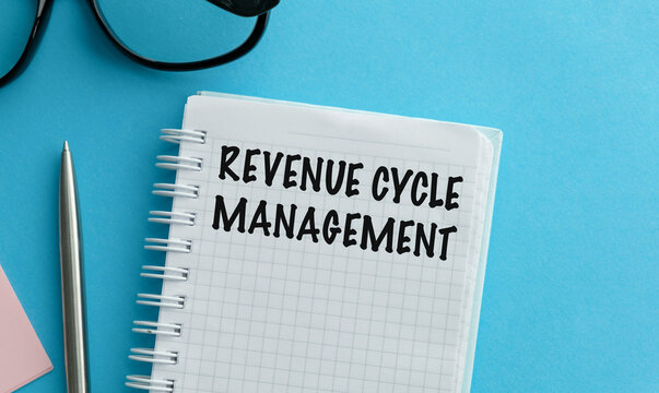 REVENUE CYCLE MANAGEMENT text written in a notebook on a blue background for financial strategy, medical billing, and corporate accounting concept.