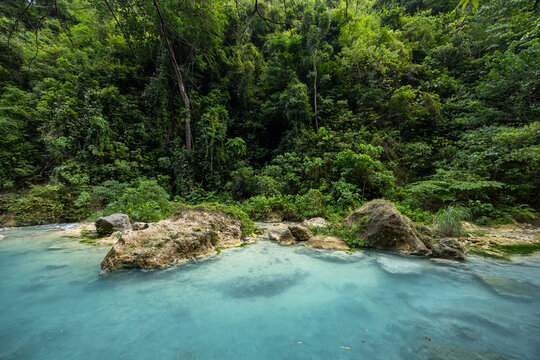 calm turquoise creek with boulders in the tropical lush jungle, Badian, Cebu, the Philippines