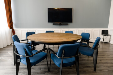 Fototapeta premium Round wooden table with blue chairs in modern office
