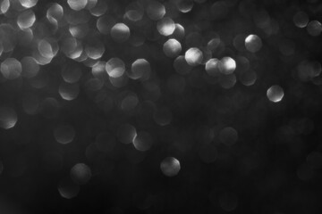 Monochrome abstract bokeh light circles on dark background creating dreamy atmosphere.