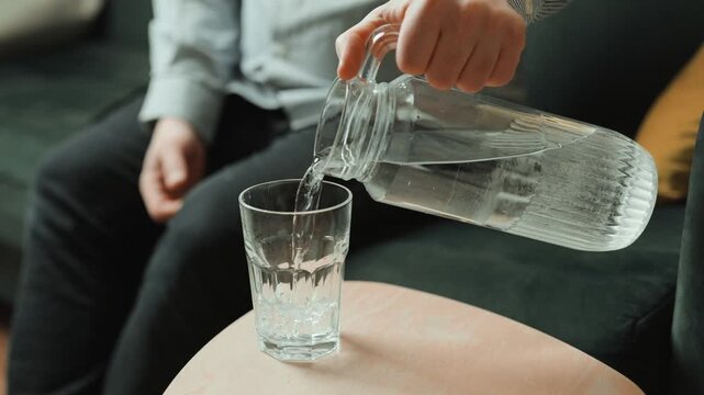 Close up of man hands pouring fresh pure water into glass.	
