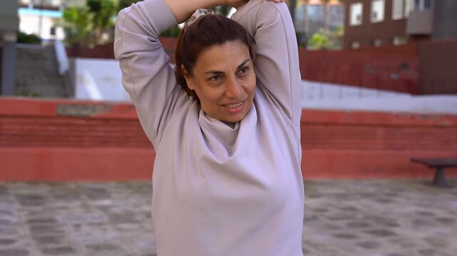 Happy matue latin woman doing stretching exercise after running sport routine in the city - Healthy elderly lifestyle concept