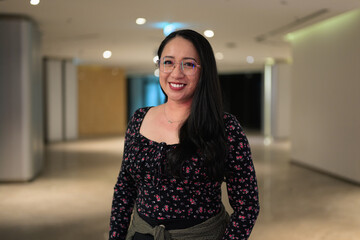 Obraz premium Portrait of smiling Asian woman wearing glasses in contemporary indoor lobby space