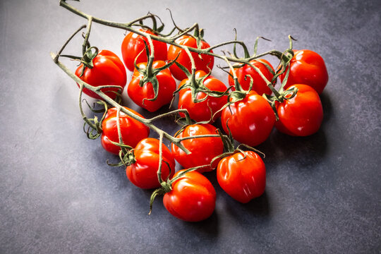 Sweet, fresh organic vine tomatoes close up on a grey background