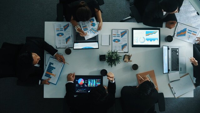 Top down aerial view of smart businessman explain financial graph to investor while business team analysis stock market investment chart at meeting table. Diverse group brainstorm idea. Directorate.