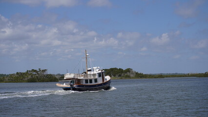 Large nautical boat sailing down a river in nature
