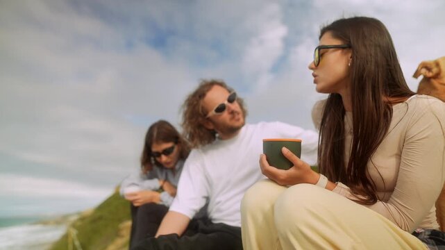 Casual gathering on rocky ledge with drinks and lively gestures