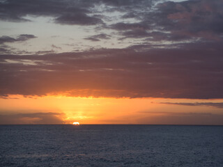 Obraz premium Vibrant Sunset Over the Atlantic Ocean - Dramatic ocean sunset with intense orange and yellow glow beneath a sky full of purple and gray storm clouds.