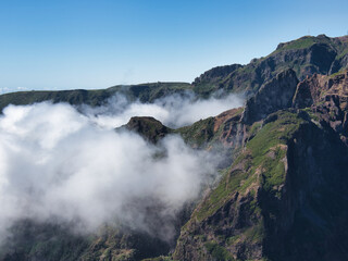 Dramatic Madeiran Mountain Peaks and Clouds - Vertical view of rugged volcanic peaks covered in green vegetation, with low clouds rolling through the deep valleys.