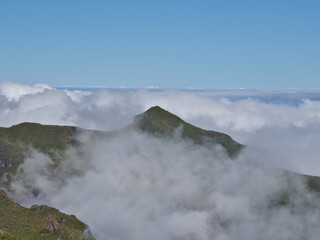 Madeira Mountain Peak Above the Clouds - Single, green, conical volcanic peak emerging from a low blanket of rolling white clouds under a clear blue sky.