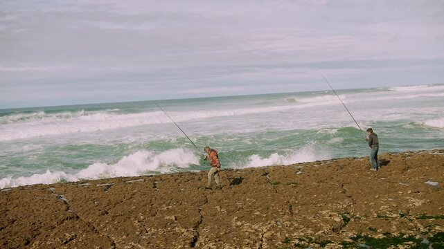 Cliffside anglers casting lines amid crashing ocean waves