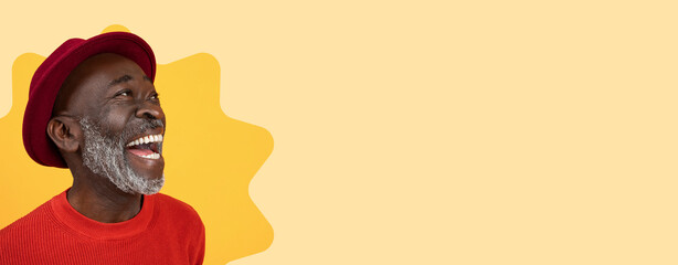 A man wearing a red sweater and a red hat laughs heartily while facing the camera. The backdrop has...