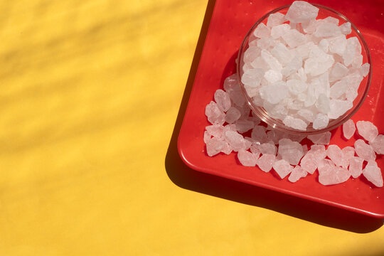 Sugar rock - Novvot - mishri sugar rock white in glass bowl on red plate on yellow background in hard sun light and hard shadow