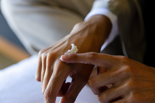Adult woman applying white cream on back of hand at home, showing cuff and jacket