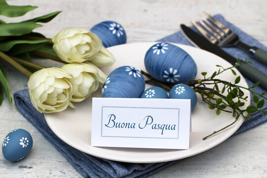 Biglietto con il testo "Buona Pasqua" su un piatto con decorazioni pasquali.