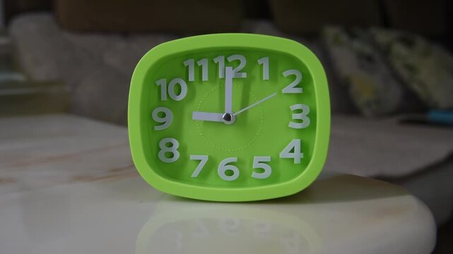 A green square plastic alarm clock is running.