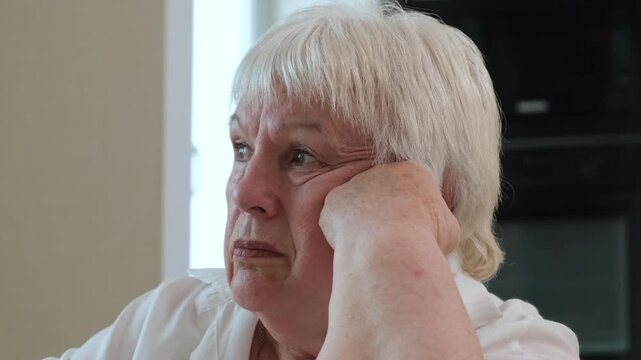 Close up sad senior woman looking away thoughtfully indoors. Concept of loneliness, aging and contemplation in retirement.