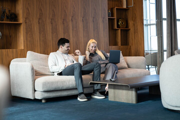 Obraz premium A man and a woman collaborating joyfully on a laptop in a modern, stylish lounge setting.