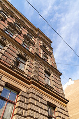 A large brick building with a lot of windows and a blue sky in the background in Riga Latvia. The building has a very old and historic look to it