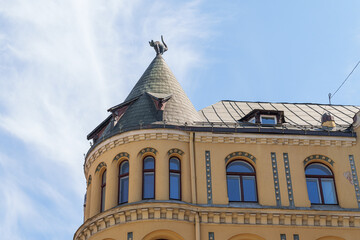 A yellow house with a semicircular tower on the side and a statue of a cat on the roof The house is located in Riga, Latvia